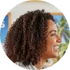 A circular profile picture of Celeste Daniels, a travel agent, smiling warmly in her beach-themed office.