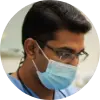 A circular profile picture of Dr. Neeraj Bhamjee, a dentist, smiling warmly.